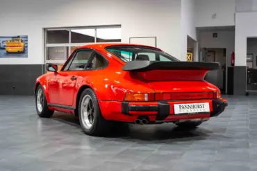 Roter Porsche 930 Turbo von hinten, ausgestellt in einem modernen Showroom