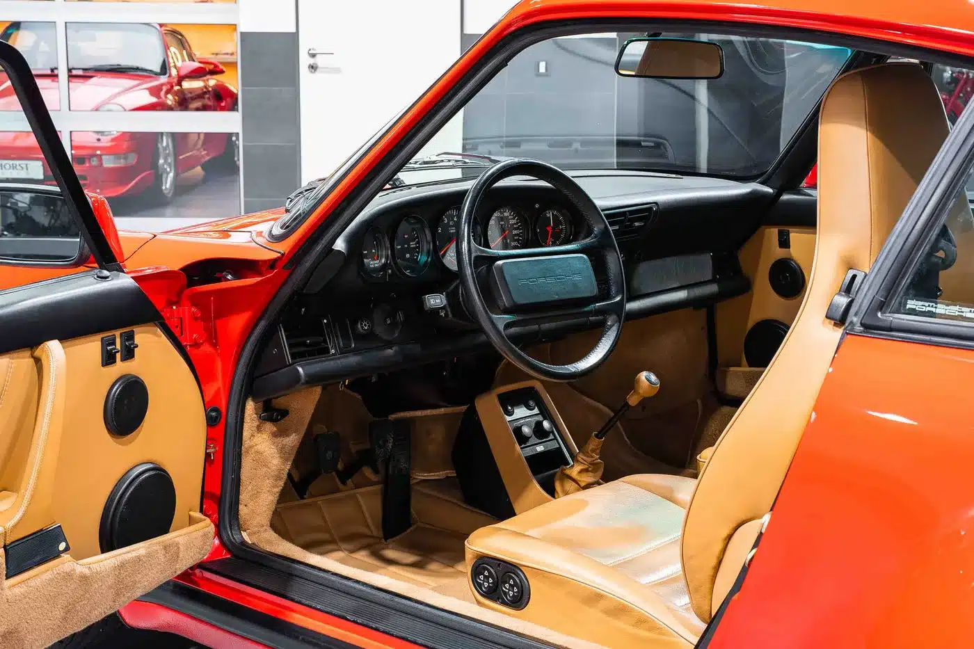 Cockpit und Innenraum eines Porsche 930 Turbo mit geöffneter Fahrertür und beigefarbener Lederausstattung.