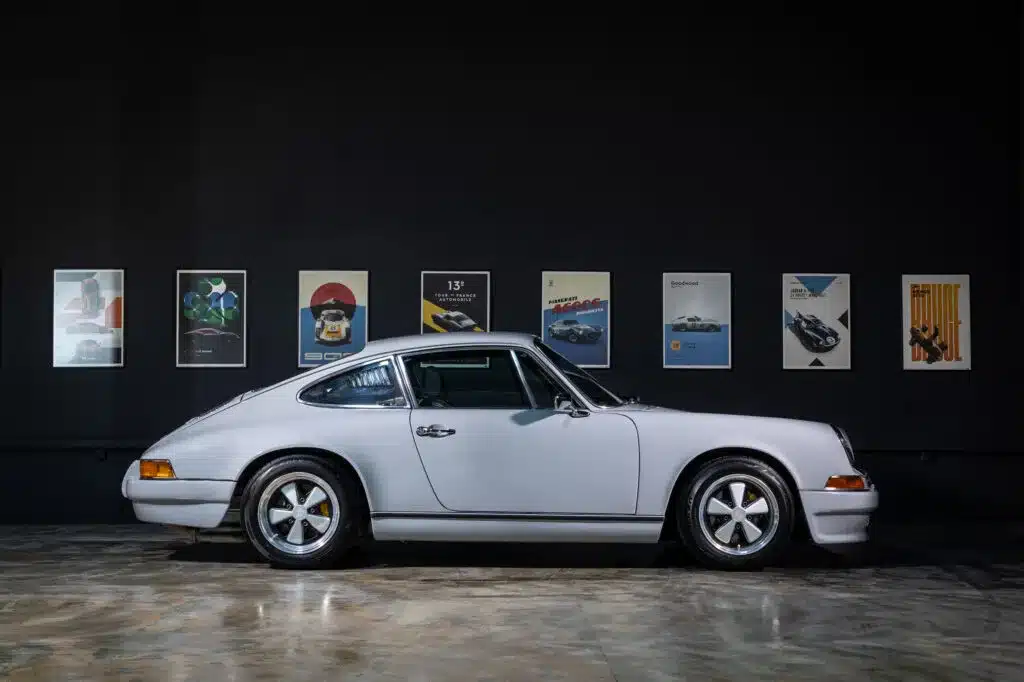 Seitenansicht eines Porsche 964 C2 Backdate vor einer dunklen Wand mit Automobilpostern.