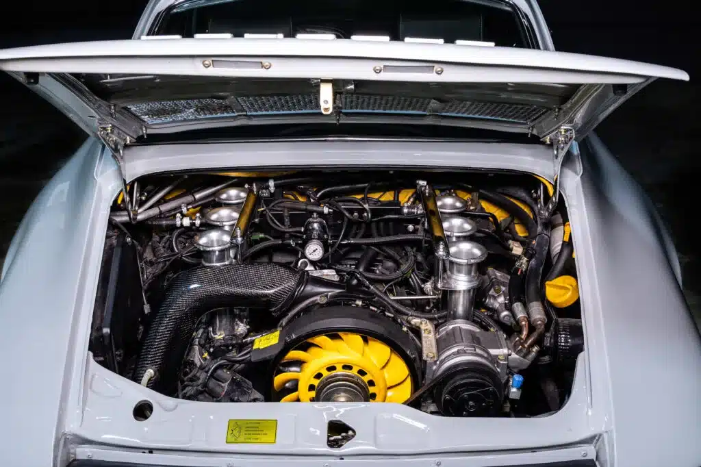 Offener Motorraum eines Porsche 964 C2 Backdate mit sichtbarem 3,6-Liter-Boxer und Carbon-Paket.