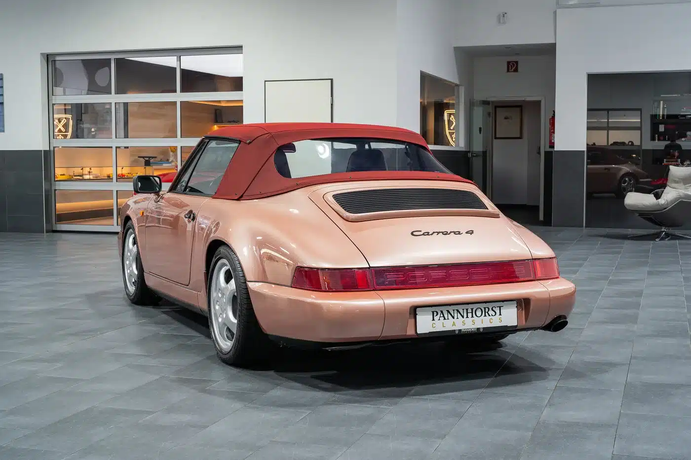 Porsche 964 Carrera 4 Cabriolet mit rotem Stoffverdeck in einem Showroom, Heckansicht