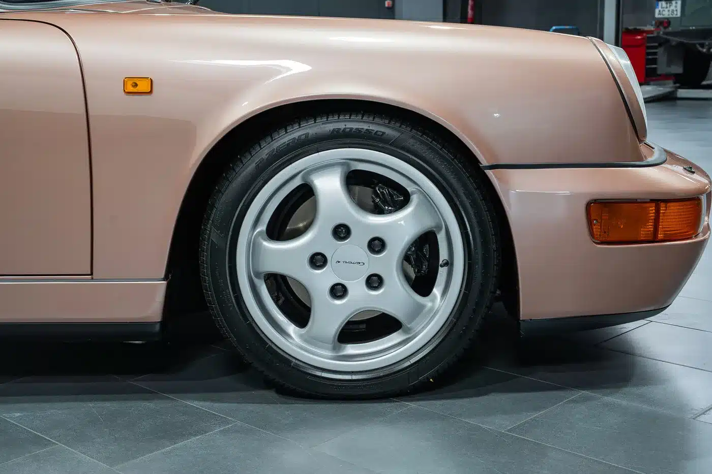 Vorderachse mit silberner Felge und Reifen an einem Porsche 964 Carrera 4 Cabriolet in roséfarbener Lackierung
