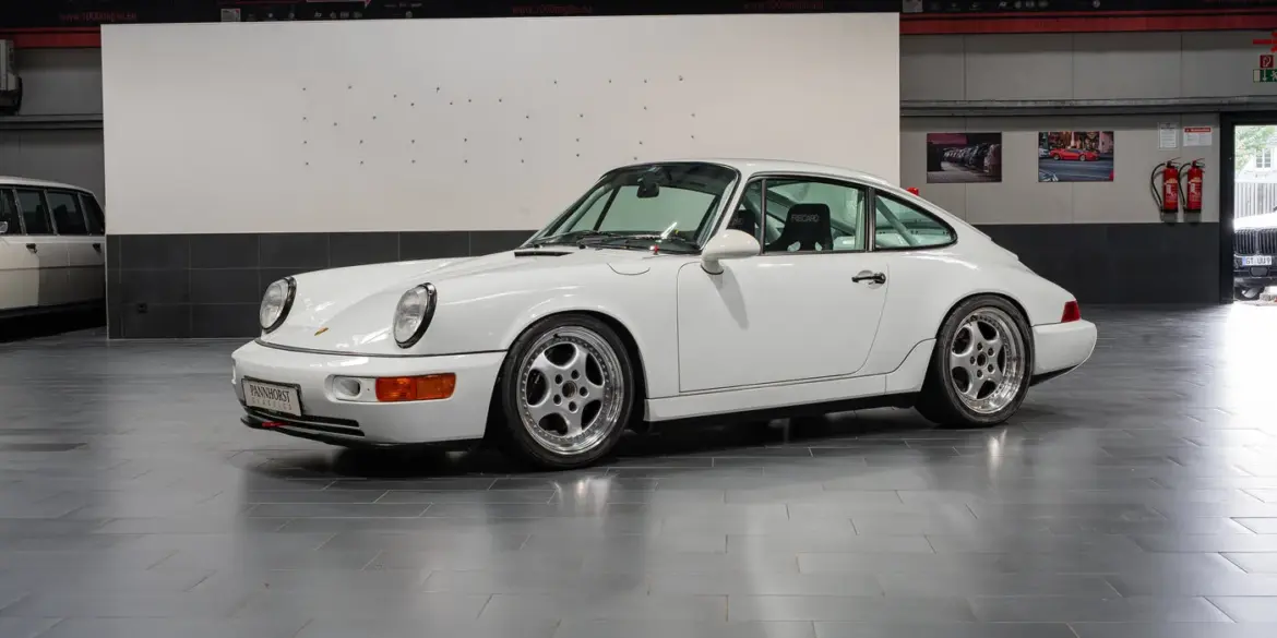 Weißer Porsche 964 Carrera Cup von 1993, Seitenansicht, im Innenraum eines Showrooms.
