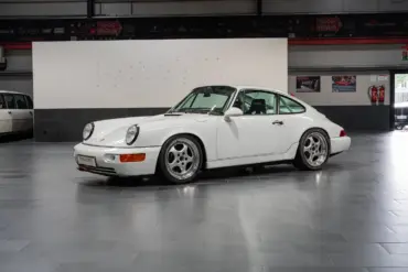 Weißer Porsche 964 Carrera Cup von 1993, Seitenansicht, im Innenraum eines Showrooms.