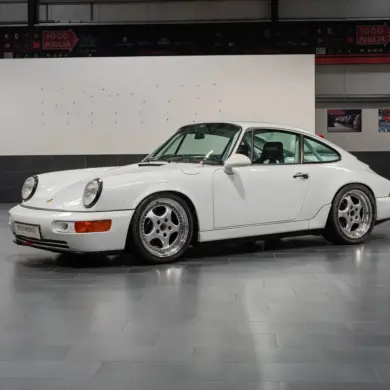 Weißer Porsche 964 Carrera Cup von 1993, Seitenansicht, im Innenraum eines Showrooms.