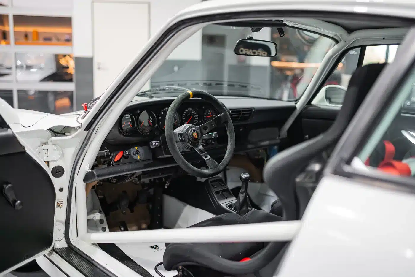 Innenansicht des Porsche 964 Carrera Cup 1993 mit Rennsport-Cockpit, Schalensitz und Überrollkäfig.