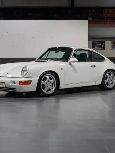 Weißer Porsche 964 RS steht in einer Hallengarage, Fahrerseite sichtbar
