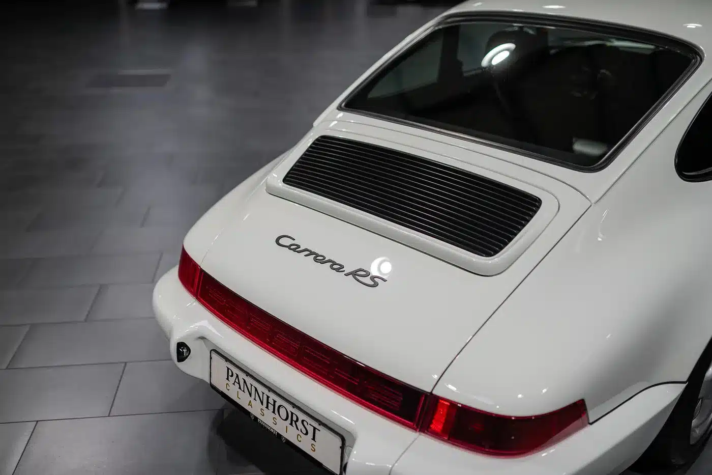 Weißer Porsche 964 Carrera RS von hinten, Detailansicht des Hecks mit Emblem und Heckleuchte.