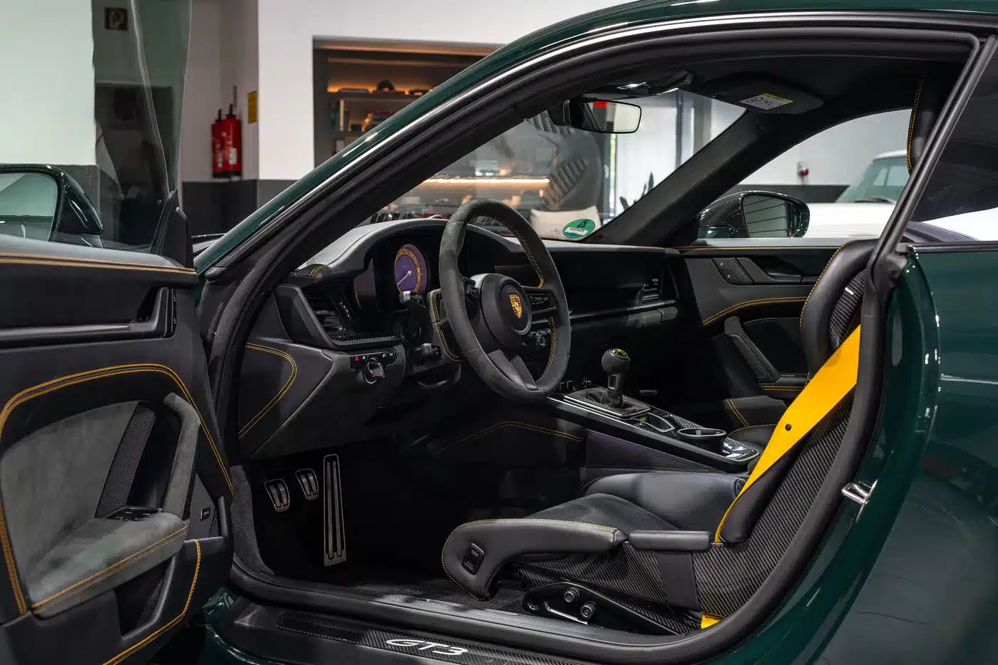 Innenraumansicht eines Porsche 992.1 GT3 mit Schalensitzen, Schaltgetriebe und gelben Ziernähten.