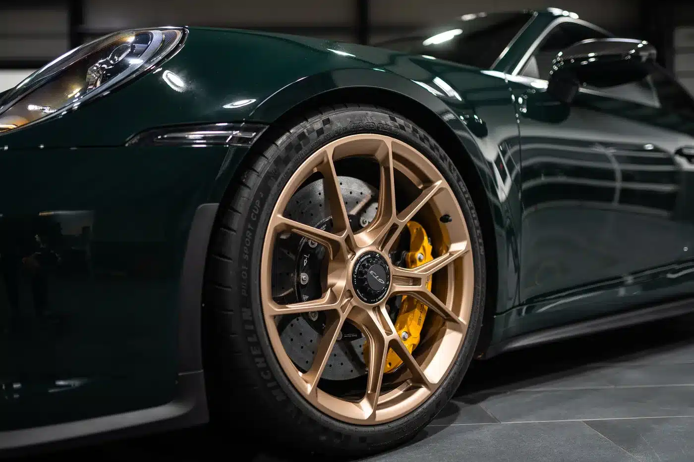 Nahaufnahme des vorderen Rads mit goldener Felge und gelber Keramikbremse eines Porsche 992.1 GT3