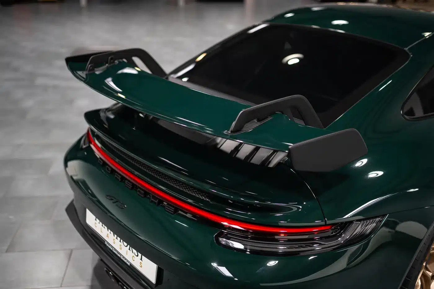 Heckpartie eines Porsche 992.1 GT3 in British Racing Green mit großem Heckflügel und markanter Rückleuchte