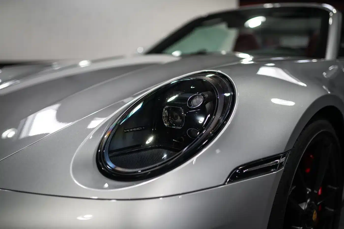 Nahaufnahme des Frontscheinwerfers eines silbernen Porsche 992 911 Carrera GTS Cabriolets.