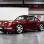 Porsche 993 Carrera 4S in Arena Red Metallic, fotografiert in einer Halle, Beigefarbenes Lederinterieur sichtbar