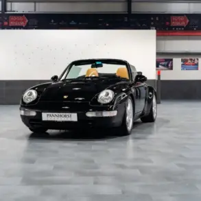 Frontansicht eines schwarzen Porsche 993 Carrera Cabriolet mit beigem Innenraum, ausgestellt in einer Halle