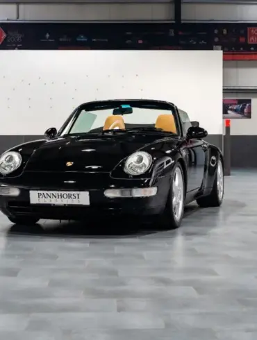Frontansicht eines schwarzen Porsche 993 Carrera Cabriolet mit beigem Innenraum, ausgestellt in einer Halle