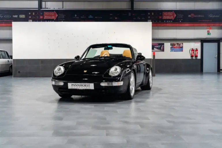 Frontansicht eines schwarzen Porsche 993 Carrera Cabriolet mit beigem Innenraum, ausgestellt in einer Halle