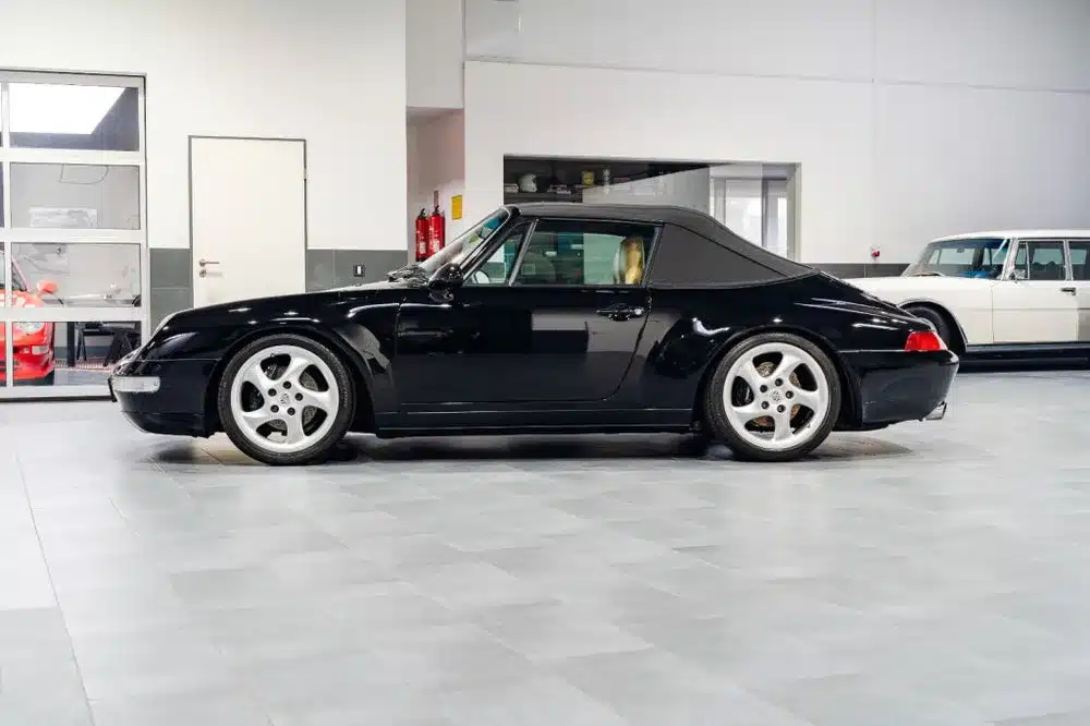 Schwarzes Porsche 993 Carrera Cabriolet mit geschlossenem Verdeck, Seitenansicht, indoor aufgenommen.