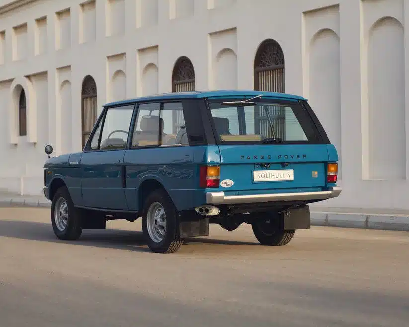Originalgetreu restaurierter Range Rover Classic von 1975 in Tuscan Blue, Heckansicht vor heller Wand.