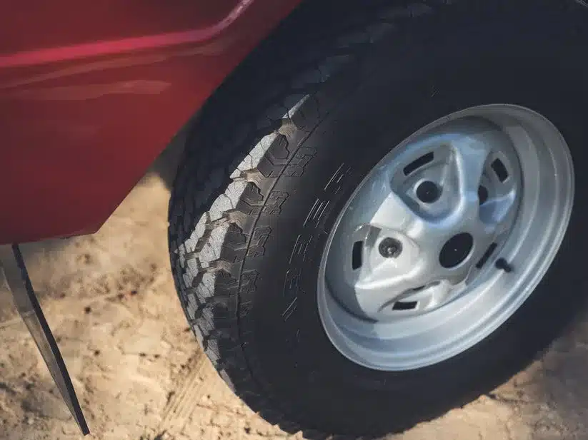 Nahaufnahme eines Reifens und Radkastens eines restaurierten Range Rover Classic 1976 in Masai Red.
