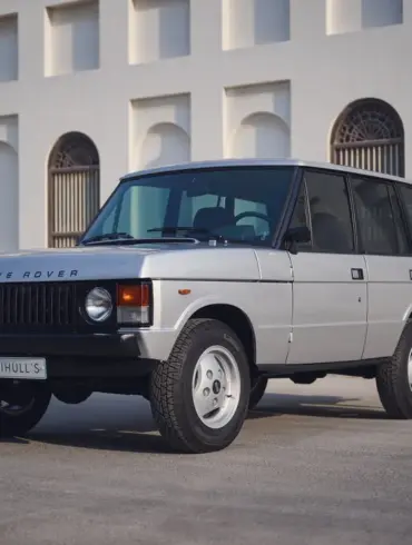 Range Rover Classic 1982 Silver Birch viertürig, aufgenommen im Originalzustand, seitlich frontal vor heller Gebäudefassade.