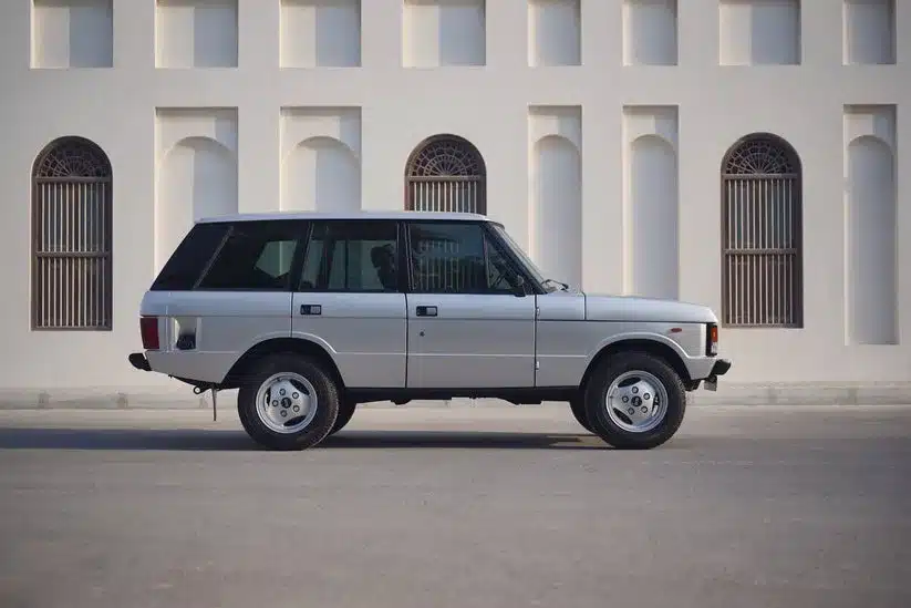 Seitenansicht eines Range Rover Classic von 1982 in Silber vor heller Gebäudefassade.