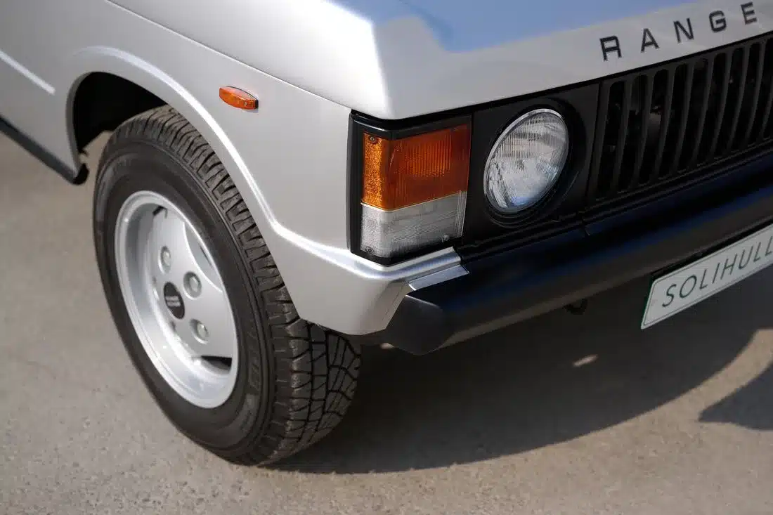 Detailansicht des vorderen linken Kotflügels mit Scheinwerfer eines silbernen Range Rover Classic von 1982.