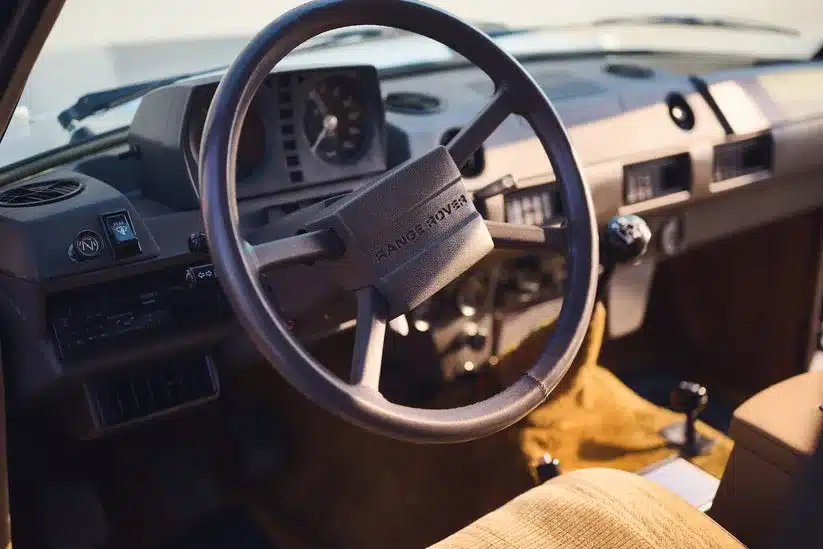 Lenkrad und Armaturenbrett eines Range Rover Classic von 1982 mit beigem Interieur.