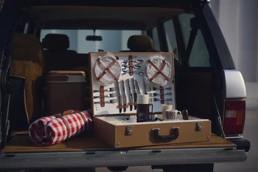 Kofferraum eines Range Rover Classic mit ausgeklapptem Picknick-Set, Geschirr und Decke.