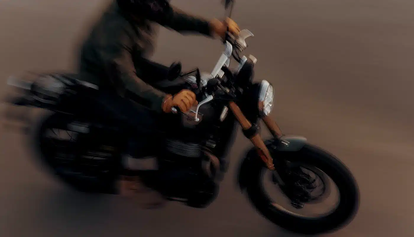 Royal Enfield Bear 650 Scrambler-Motorrad mit Fahrer auf der Straße, Fokus auf Retro-Design und goldener Upside-down-Gabel