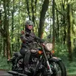 Motorradfahrer auf einer Royal Enfield Bullet 350 im Wald, modernes Modell in Schwarz.