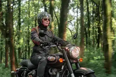 Motorradfahrer auf einer Royal Enfield Bullet 350 im Wald, modernes Modell in Schwarz.