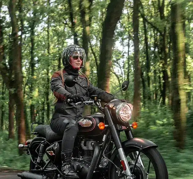 Motorradfahrer auf einer Royal Enfield Bullet 350 im Wald, modernes Modell in Schwarz.