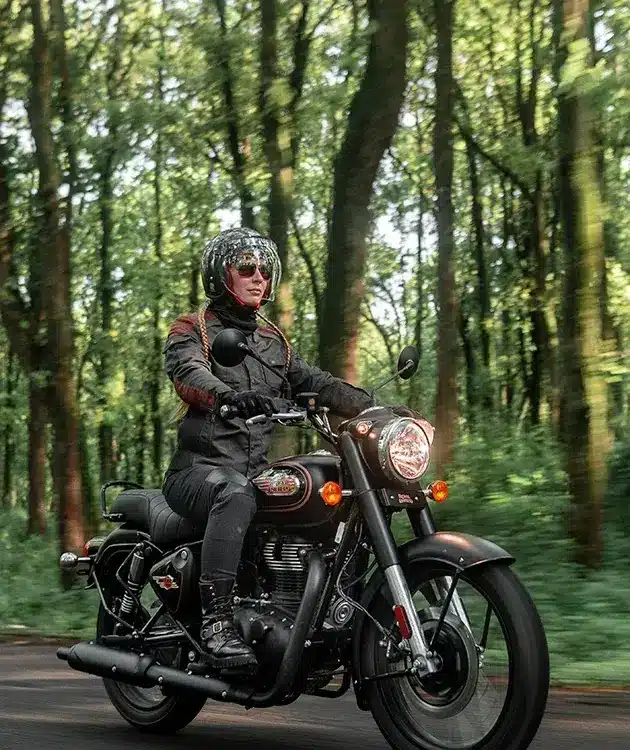 Motorradfahrer auf einer Royal Enfield Bullet 350 im Wald, modernes Modell in Schwarz.