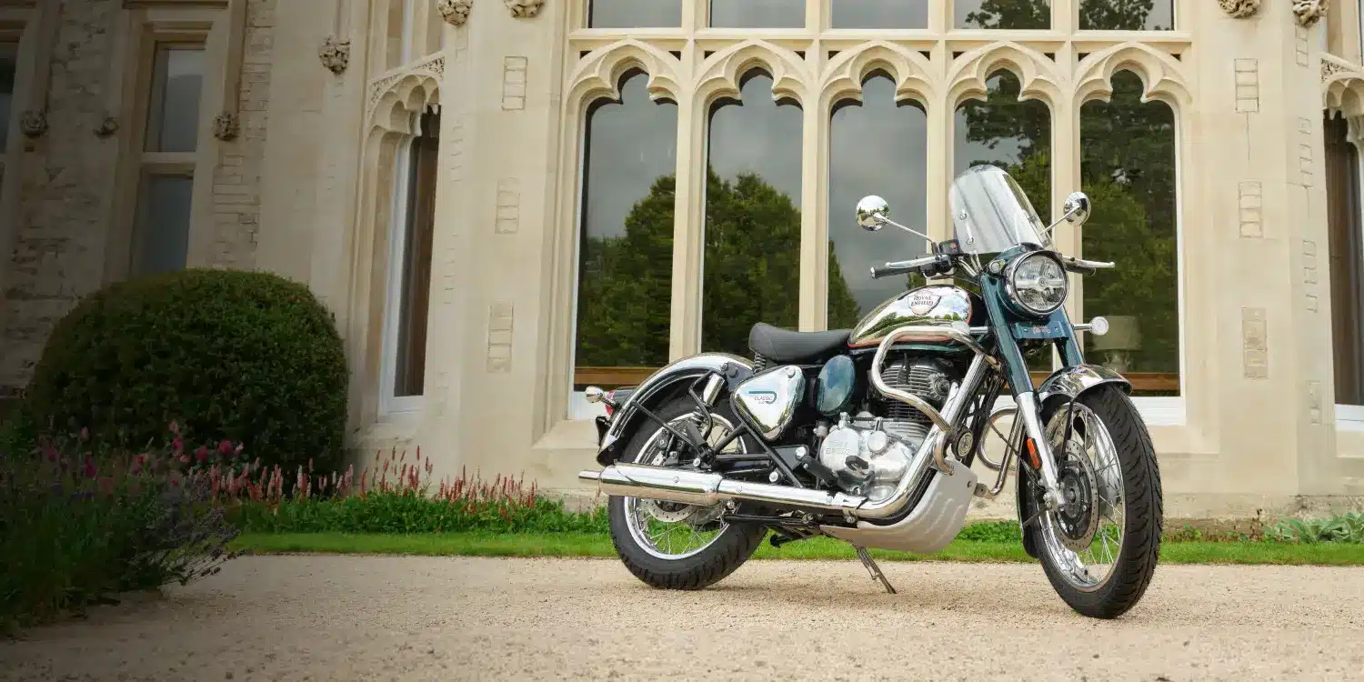 Royal Enfield Classic 350 Motorrad, Chrom und Blau, geparkt vor einem Gebäude mit gotischen Fenstern