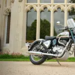 Royal Enfield Classic 350 Motorrad, Chrom und Blau, geparkt vor einem Gebäude mit gotischen Fenstern