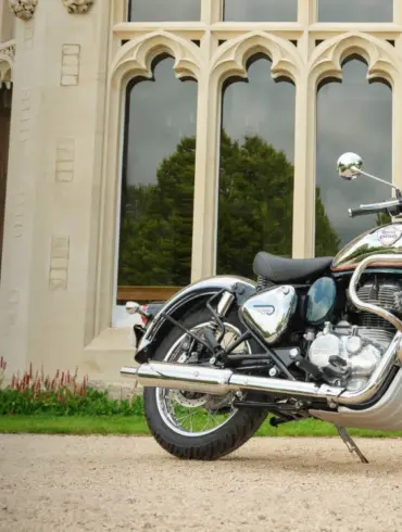 Royal Enfield Classic 350 Motorrad, Chrom und Blau, geparkt vor einem Gebäude mit gotischen Fenstern