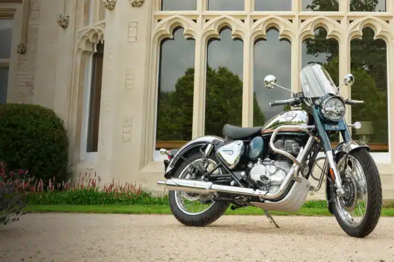 Royal Enfield Classic 350 Motorrad, Chrom und Blau, geparkt vor einem Gebäude mit gotischen Fenstern