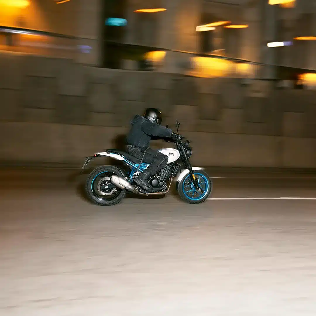 Fahrer auf einer Royal Enfield Guerrilla 450 fährt durch eine nächtliche Stadtstraße.