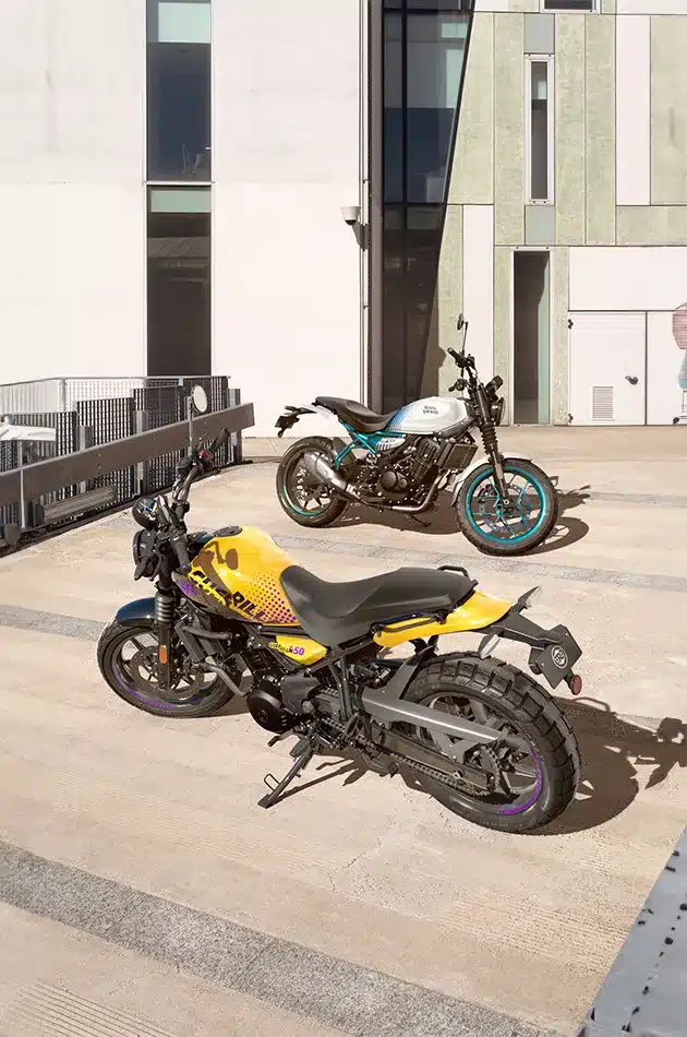 Zwei Royal Enfield Guerrilla 450 Motorräder nebeneinander geparkt, gelb und weiß-blau, in urbaner Kulisse