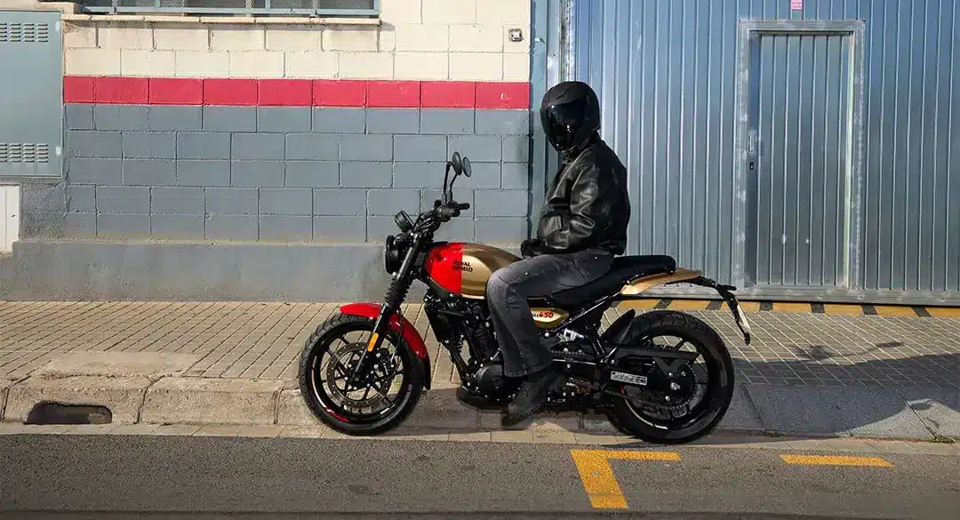 Motorradfahrer sitzt auf einer Royal Enfield Guerrilla 450 vor einer Halle in der Stadt.