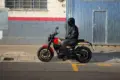 Motorradfahrer sitzt auf einer Royal Enfield Guerrilla 450 vor einer Halle in der Stadt.