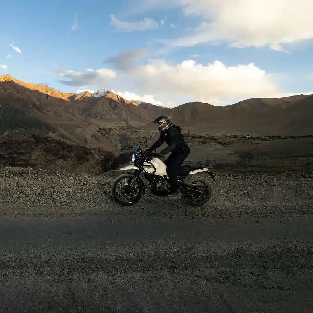 Royal Enfield Himalayan 450 Motorrad mit Fahrer auf Schotterstraße im Gebirge