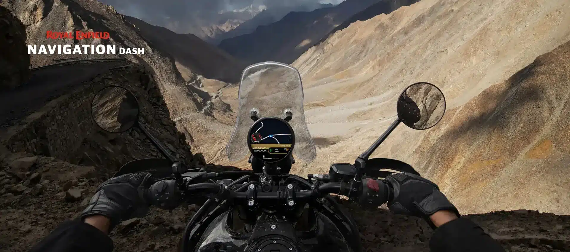 Royal Enfield Himalayan 450 Cockpitansicht mit Navigationsdisplay, Berglandschaft und kurviger Hochgebirgsstraße im Hintergrund.