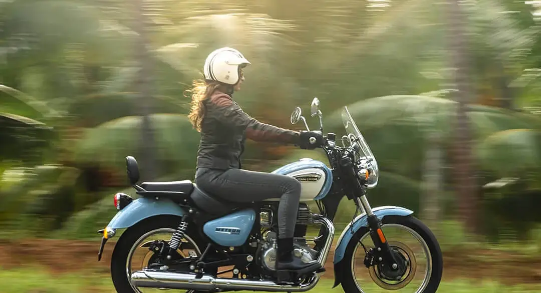 Royal Enfield Meteor 350 Aurora Blue mit Fahrerin auf Landstraße vor Naturkulisse