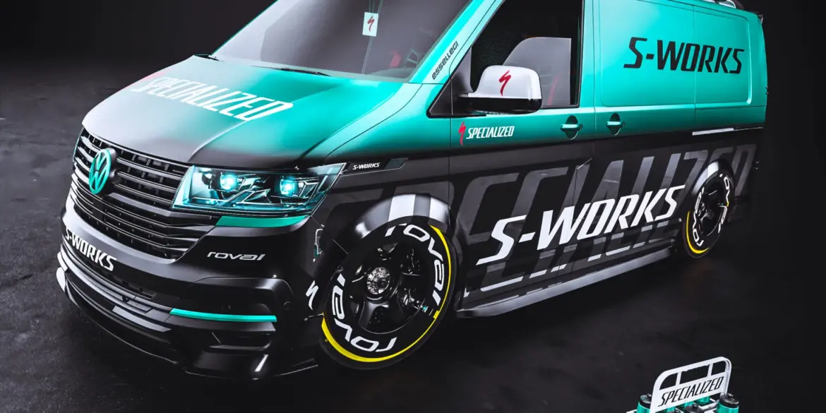 VW Transporter mit Specialized S-Works-Folierung, blauen und schwarzen Akzenten, RAYS TE37 Felgen und zwei Rennrädern auf dem Dachträger.