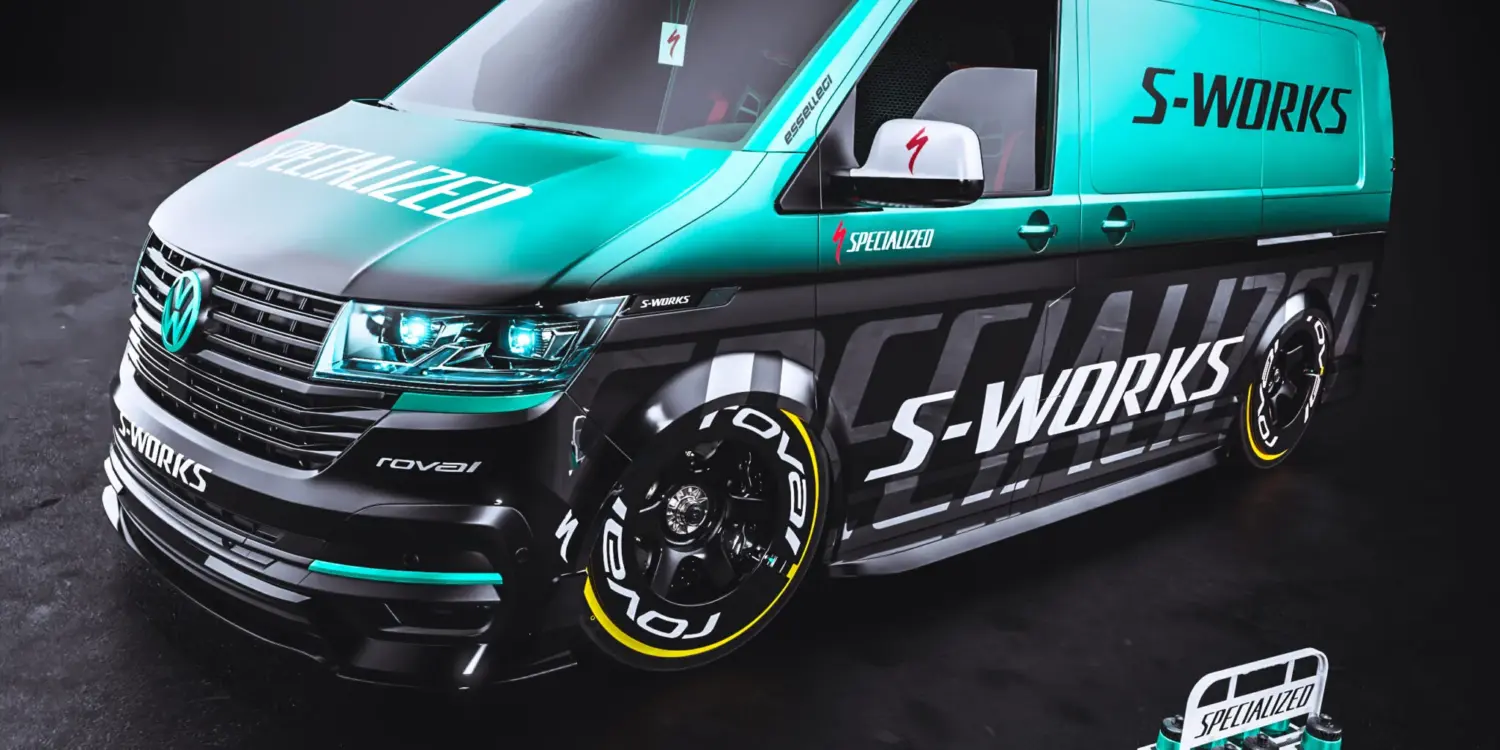 VW Transporter mit Specialized S-Works-Folierung, blauen und schwarzen Akzenten, RAYS TE37 Felgen und zwei Rennrädern auf dem Dachträger.