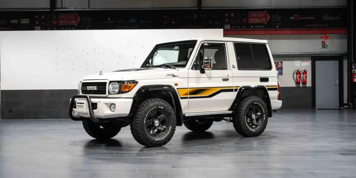 Weißer Toyota Land Cruiser 70 Jahre Edition mit klassischen Geländewagen-Details in einer Halle.