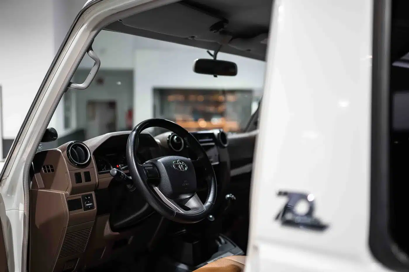 Blick in den Innenraum eines Toyota Land Cruiser 70 Jahre Edition mit Lenkrad, braunen Ledersitzen und 70 Jahre-Emblem an der Tür
