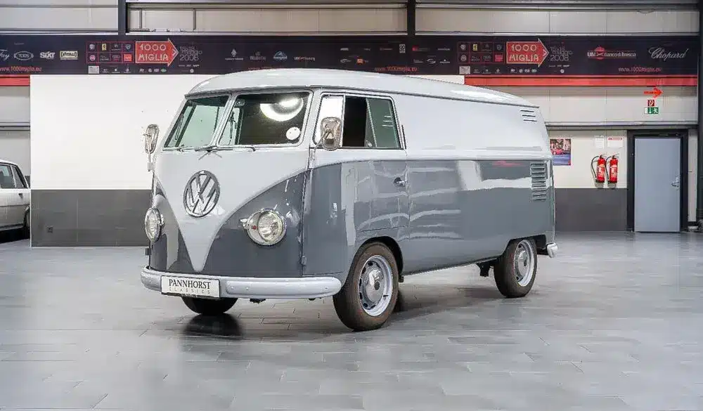 Grau lackierter Volkswagen VW T1 Kastenwagen Baujahr 1956 in einer Halle, frontal schräg fotografiert.