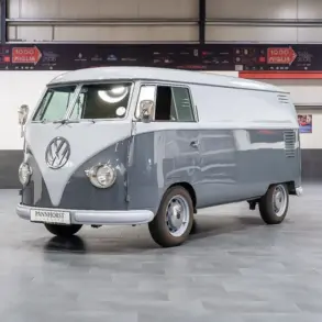 Grau lackierter Volkswagen VW T1 Kastenwagen Baujahr 1956 in einer Halle, frontal schräg fotografiert.